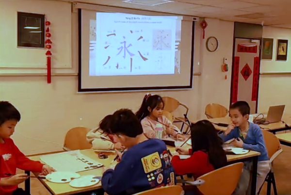 孩子们练习毛笔笔画，屏幕上是“永字八法”